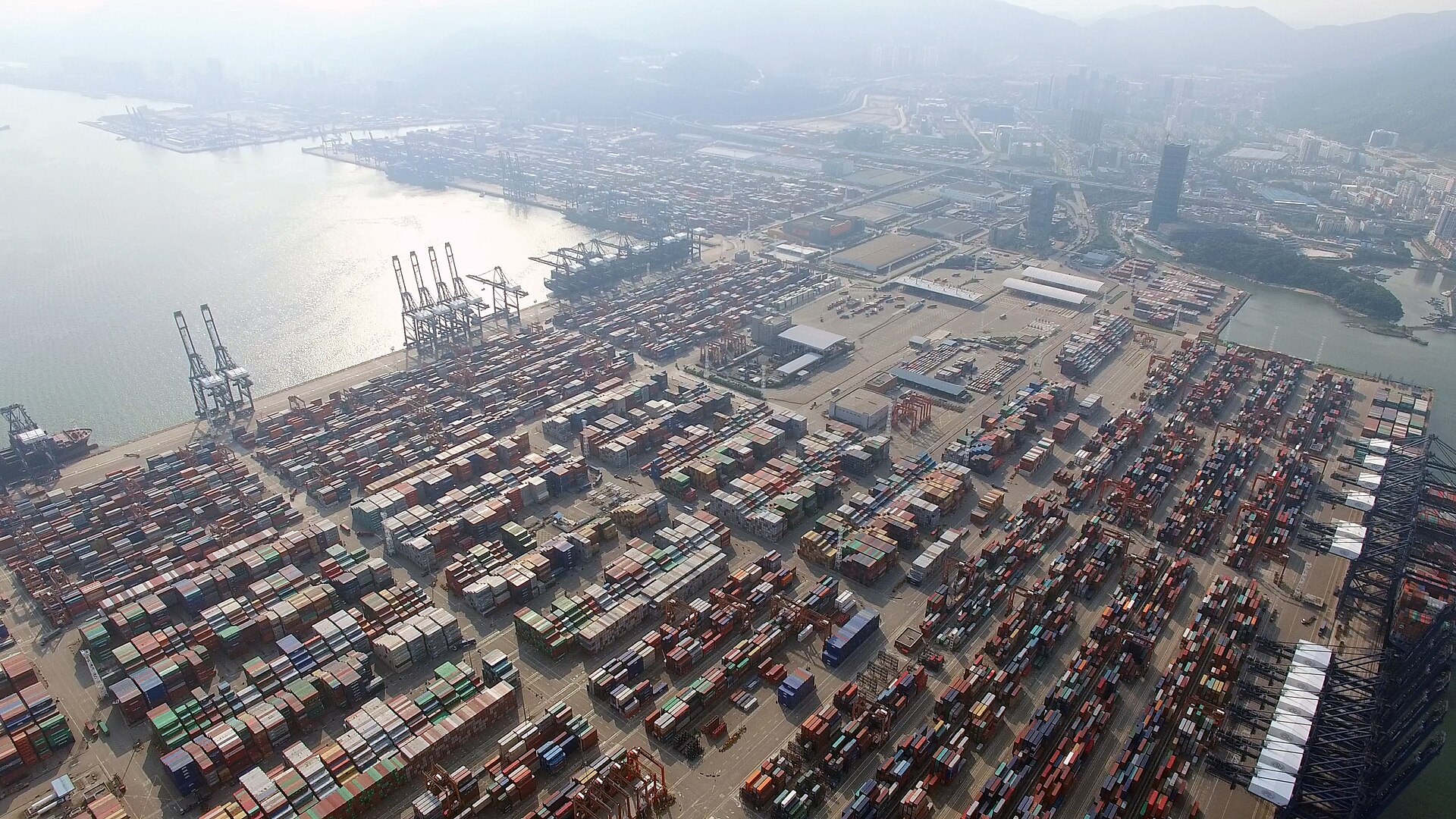 Aerial real photograph of Yantian Port in Shenzhen with container yards, cranes and coastal mountains
